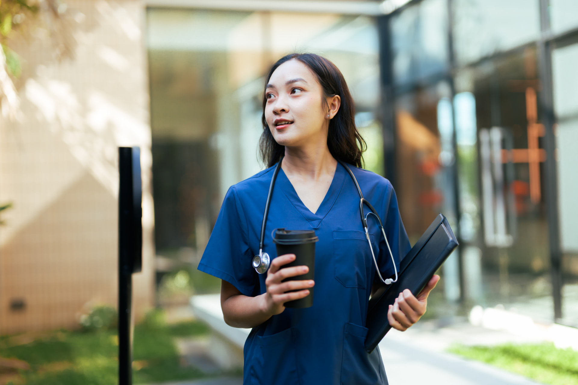 Two healthcare professionals wearing black HITO scrub sets in a hospital corridor